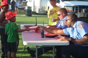 Demopolis Police officers hand out goodies and coloring pages to local children during a previous year’s event. This year’s National Night Out will be on August 6.
